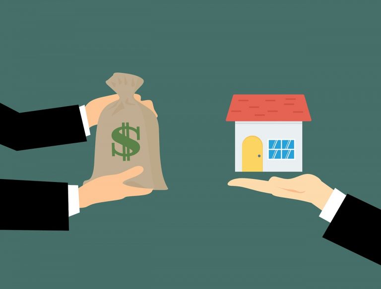 hands holding a paper with a house in the background