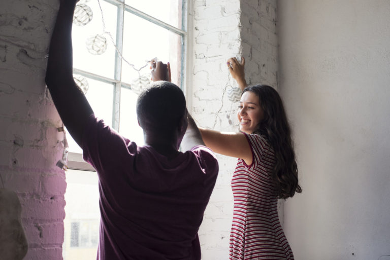 Young couple decorating window with fairylights