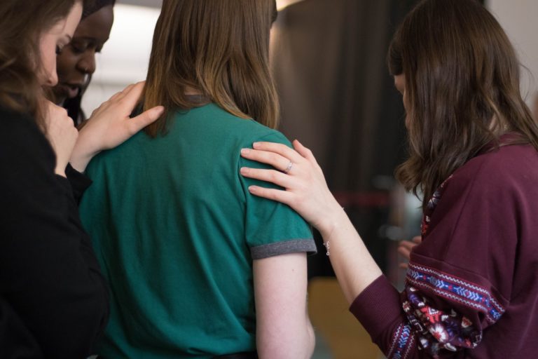 a group of people looking at a person in a green shirt