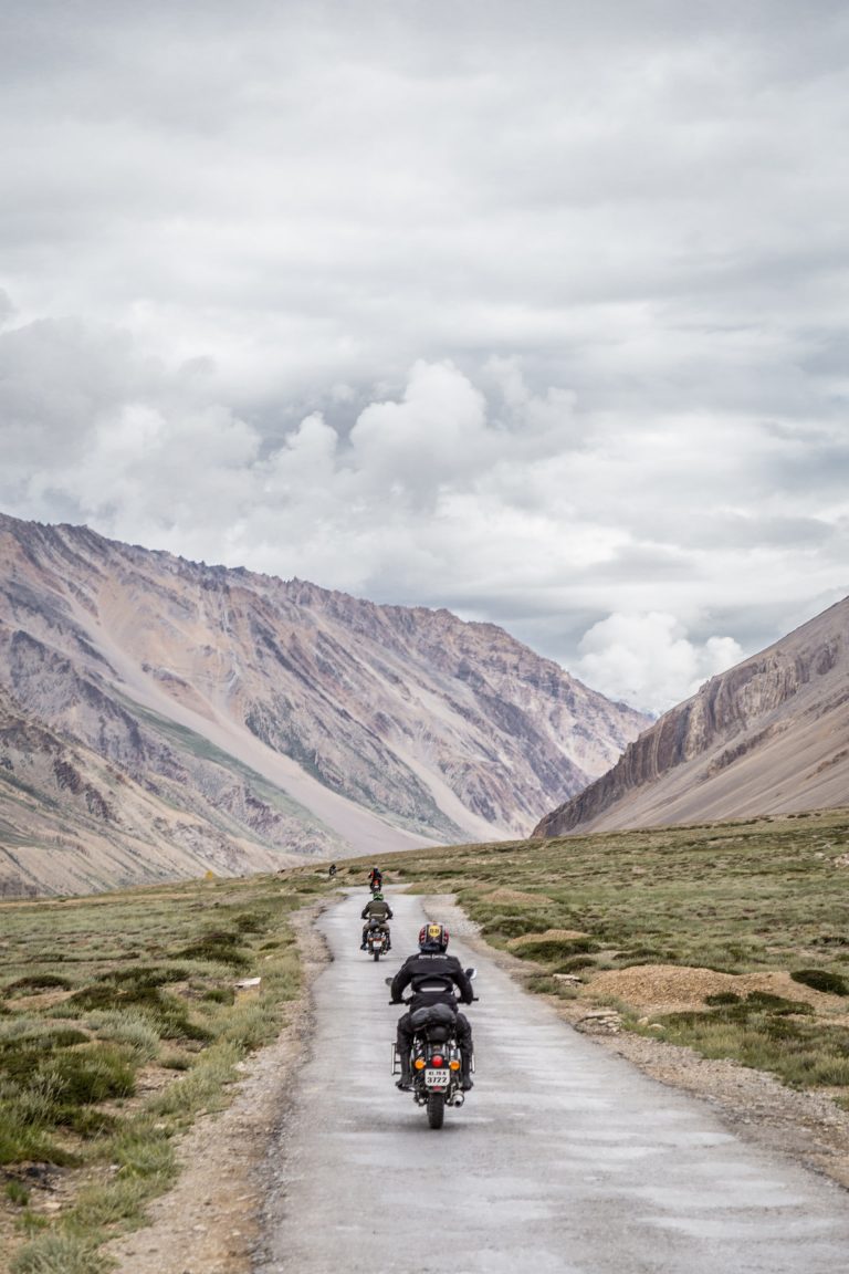 a group of people riding motorcycles on a road with mountains in the background