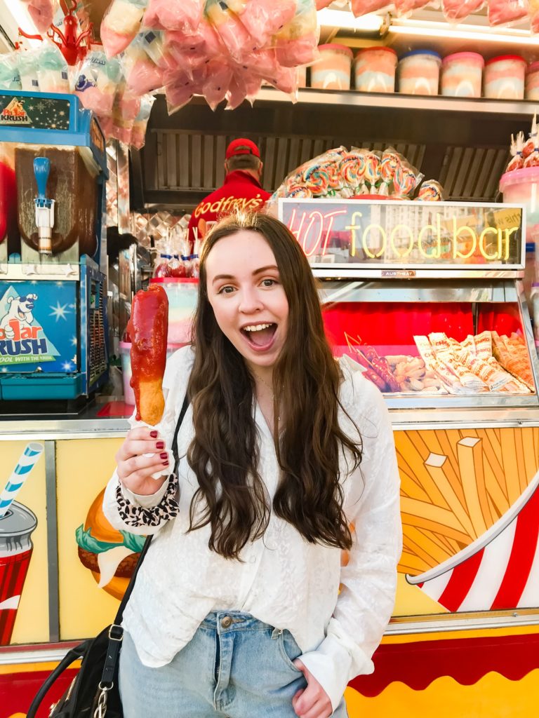 a person smiling in front of a display of donuts