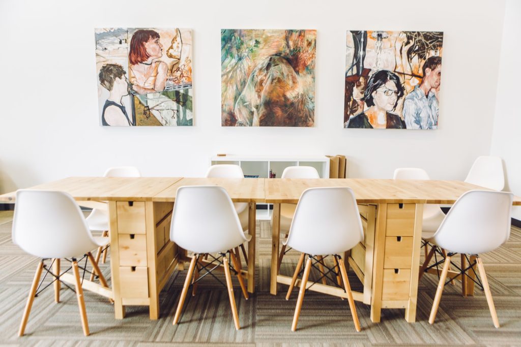 a table with chairs and a few paintings on it